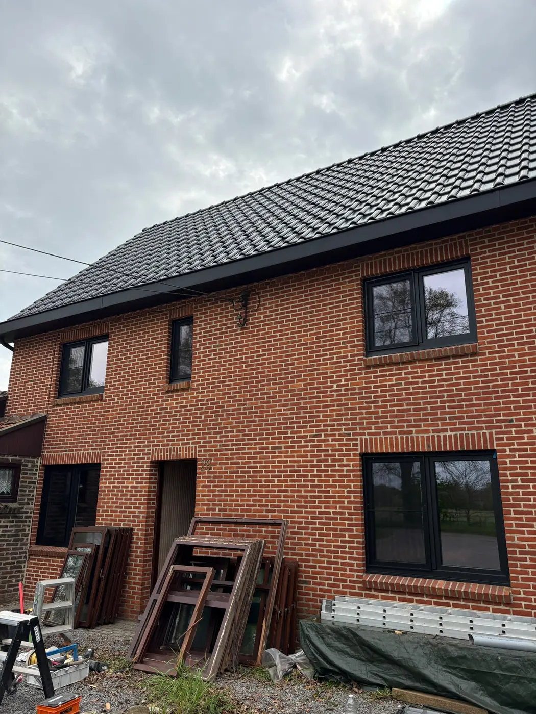 Woning tijdens renovatie met nieuw geplaatste donkere ramen